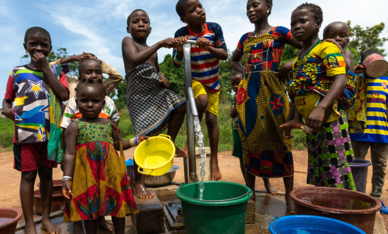 African children collecting water from a well with a pump, Bafing, Yo, Ivory Coast