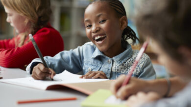 Portrait of schoolgirl drawing at the school library and laughing