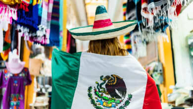 Young woman walking and holding a mexican flag at street market