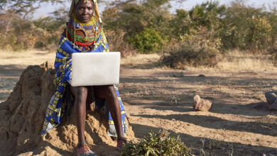 Traditional Muhila woman, wearing sneakers,neakers working on her laptop, Kehamba, Chibia, Angola