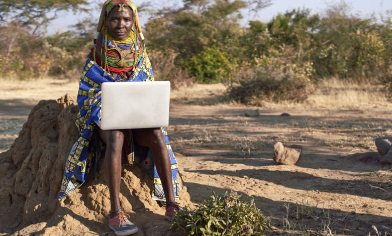 Traditional Muhila woman, wearing sneakers,neakers working on her laptop, Kehamba, Chibia, Angola