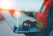 A person is using a laptop with a wind turbine on the screen