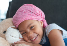 Happy girl with cancer hugs teddy bear