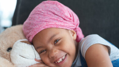 Happy girl with cancer hugs teddy bear