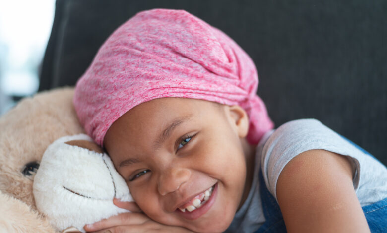 Happy girl with cancer hugs teddy bear