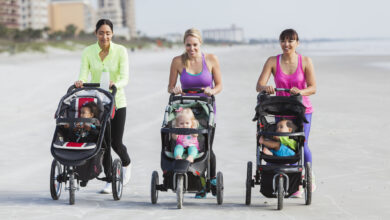 Three mothers and babies in strollers walking on beach
