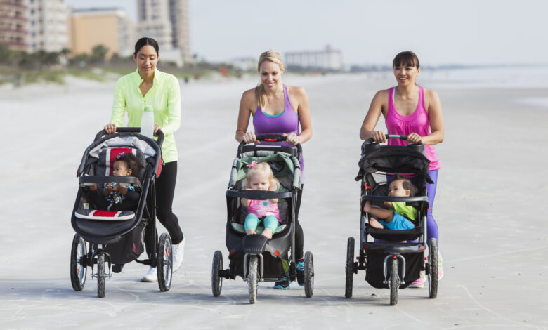 Three mothers and babies in strollers walking on beach