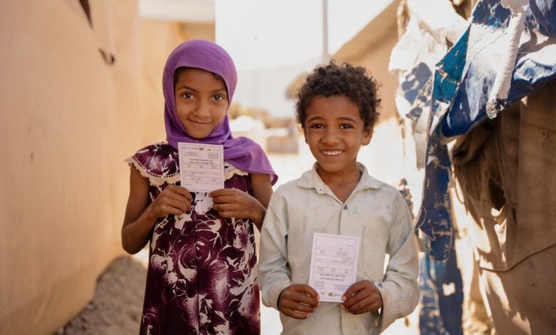 Two children hold their vaccination cards after receiving the oral cholera vaccine in Sannah camp in Al Dhale'e, Yemen.