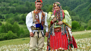 Shpetim Draga, a young man from Shishtavec, Albania, in traditional Goran costume, walks with his wife and young son on a meadow full of daffodils. June 05 2022