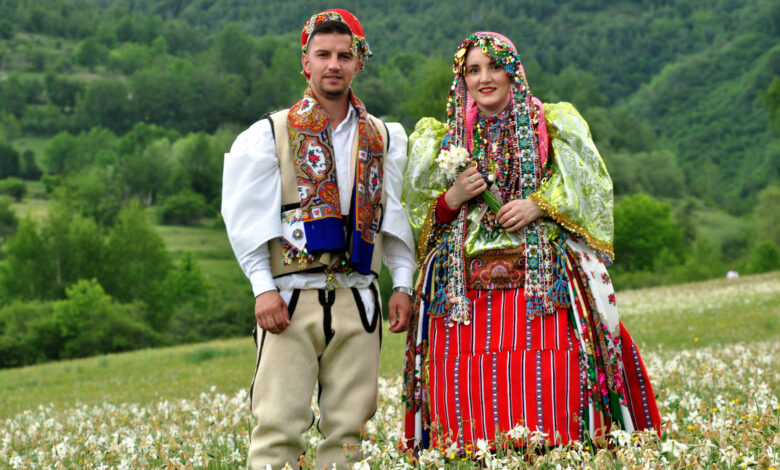 Shpetim Draga, a young man from Shishtavec, Albania, in traditional Goran costume, walks with his wife and young son on a meadow full of daffodils. June 05 2022