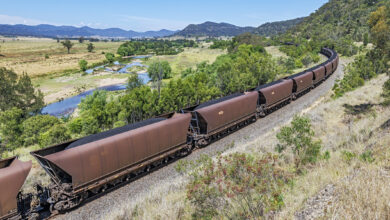 Loaded Black Thermal Coal Train in Beautiful River Valley Environment