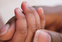 Mother holds baby's hand. Close-up