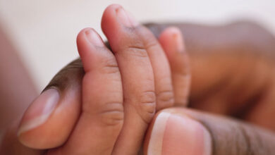 Mother holds baby's hand. Close-up