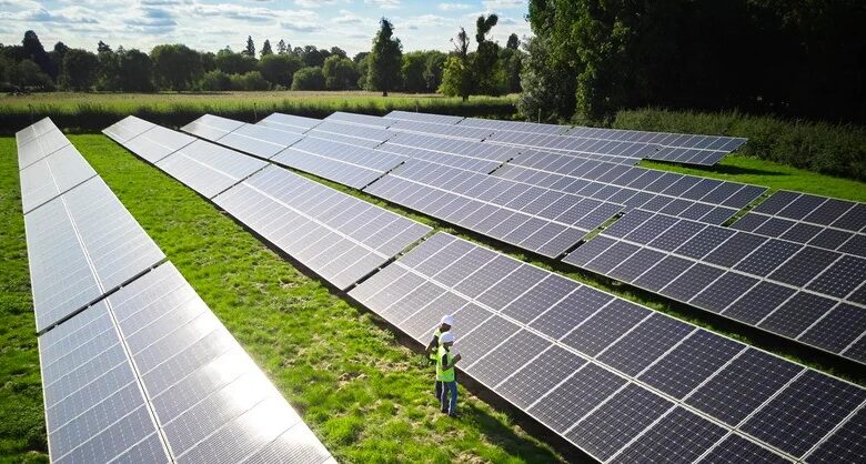 Engineers inspect solar panels in a field