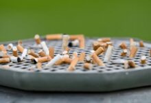 Cigarette butts stuck on a garbage can with an ashtray