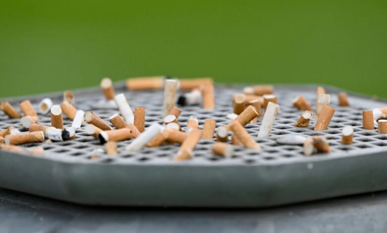 Cigarette butts stuck on a garbage can with an ashtray