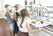 Students standing side by side taking lunch in school cafeteria