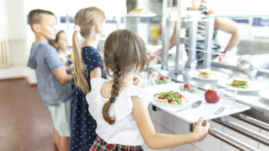 Students standing side by side taking lunch in school cafeteria
