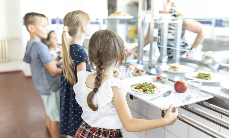 Students standing side by side taking lunch in school cafeteria