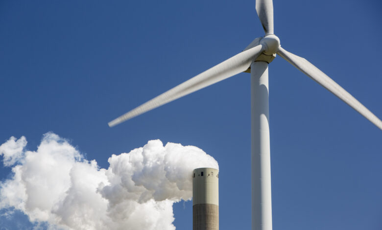 A wind turbine with emissions from a coal fired power station in Amsterdam, Netherlands.