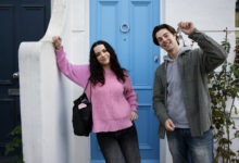 A young couple standing outside the front door of their new home