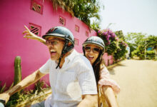 Medium shot mischievous senior couple driving motor scooter on street