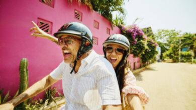 Medium shot mischievous senior couple driving motor scooter on street