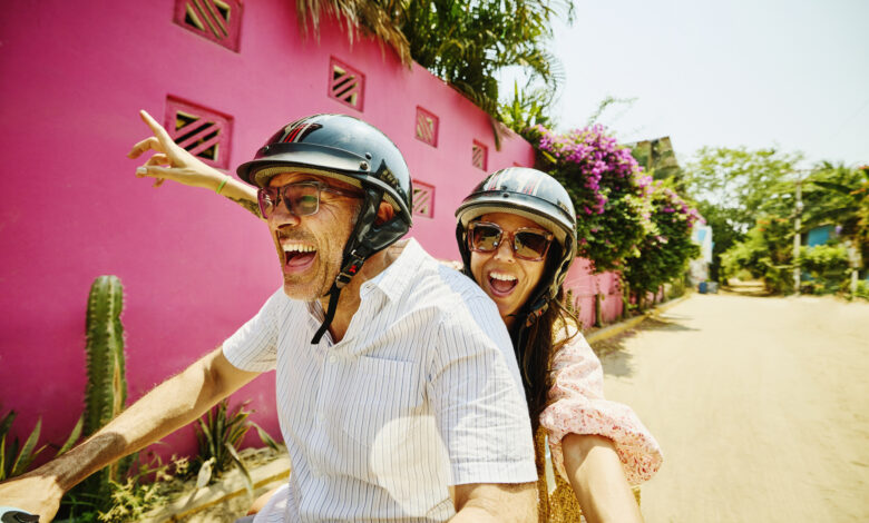 Medium shot mischievous senior couple driving motor scooter on street