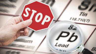 Stop heavy metals - Concept image with hand holding a stop sign against a Lead chemical element with the Mendeleev periodic table seen through a magnifying glass