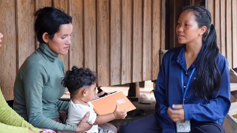 Health volunteer in Cambodia speaks with mother and her young child