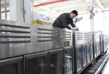worker injecting refrigerant into freezers on a production line at a kitchen utensils manufacturer in Binzhou, Shandong province.