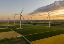 Sunset Over Wind Turbines in Vast Agricultural Fields with Golden and Green Crops