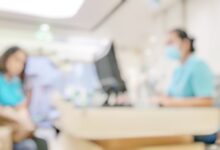 Blur abstract background of patients register at reception desk in hospital. Blurry nurse receptionists taking care new customers in medical clinic. Defocus reception area with worker. Healthcare concept.
