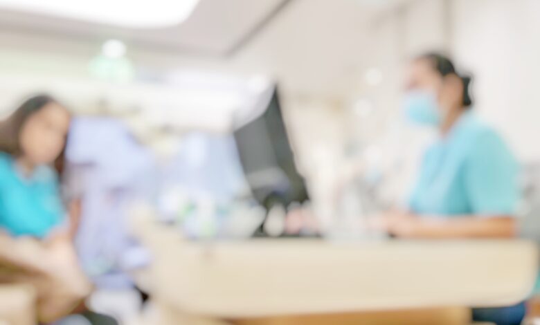 Blur abstract background of patients register at reception desk in hospital. Blurry nurse receptionists taking care new customers in medical clinic. Defocus reception area with worker. Healthcare concept.